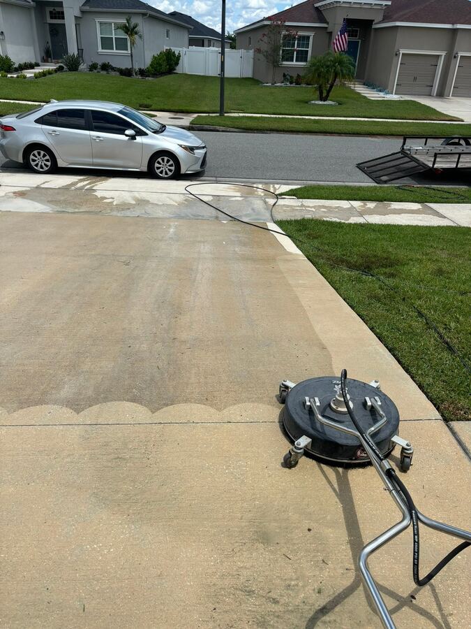 Concrete driveway pressure washing in Lakeland, FL, showing the clean line between washed and unwashed concrete